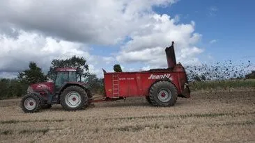 épandage par un tracteur et remorque dans un champ